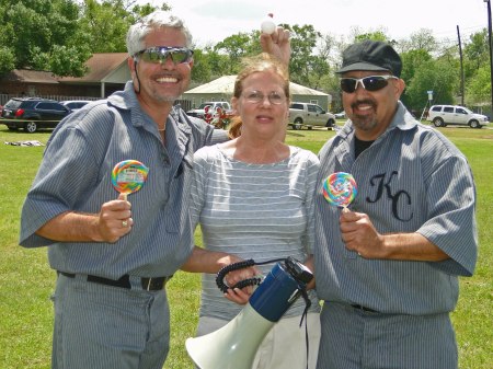 Nancy of the Sealy Group awards the Lollipos that went to the winners of the Egg Tossing Contest as Clay Meritt (L) hold the winning egg over her head and Dave Flores looks on in pleasure.